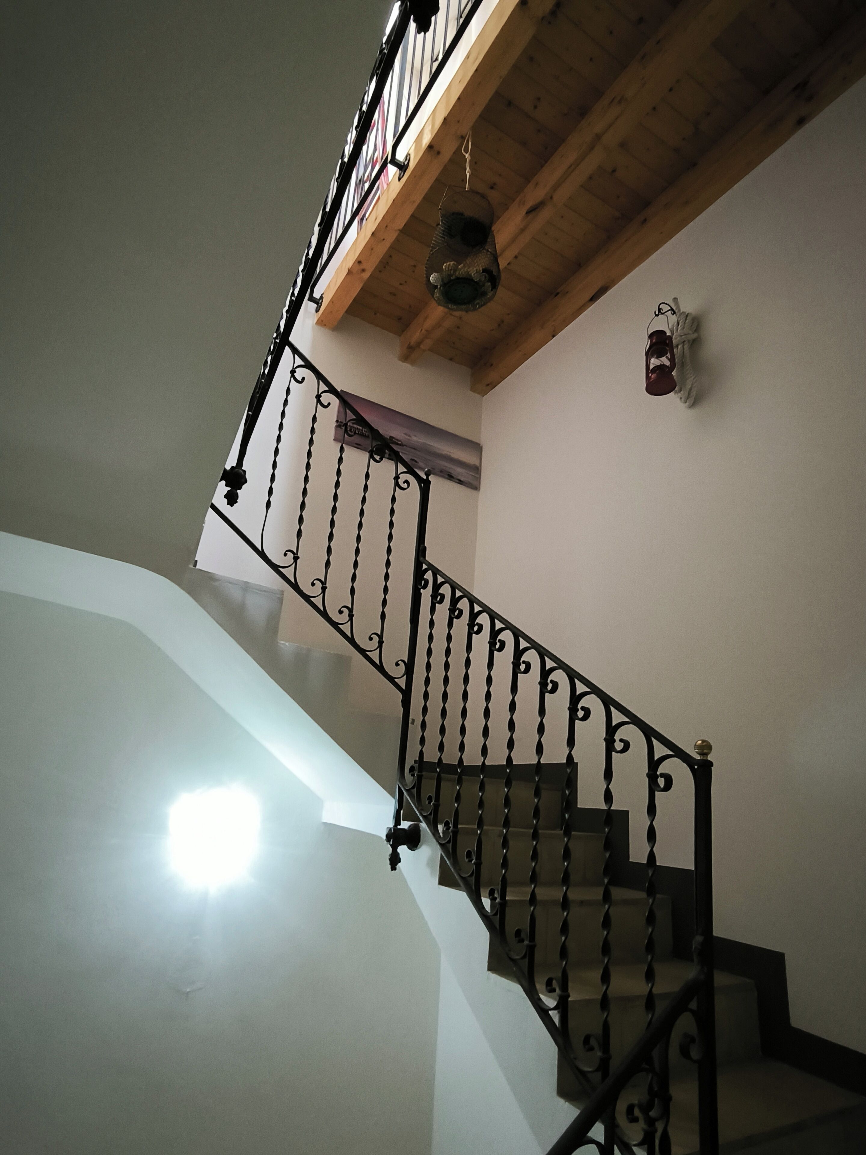 Un escalier avec un plafond en bois et une rampe en métal.