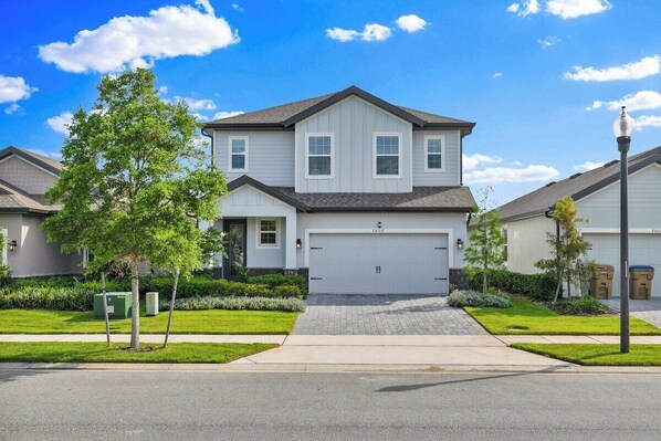 A two-story residential house with a garage, a driveway, and a well-maintained lawn.