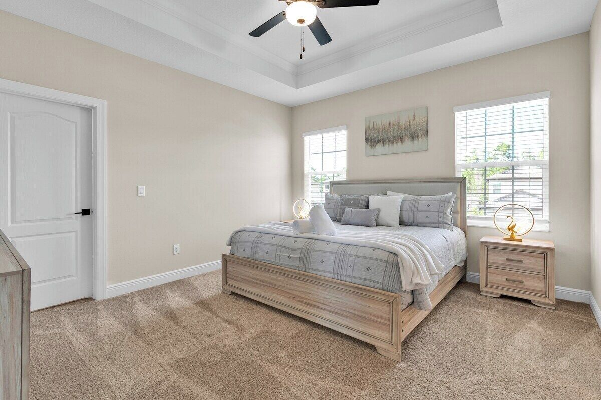 A bedroom with a bed, bedside tables, a ceiling fan, and a window with blinds.