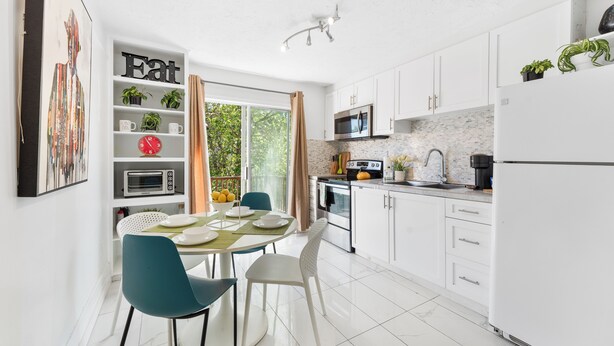 A modern kitchen with white cabinets, a dining table with chairs, and a kitchen island.