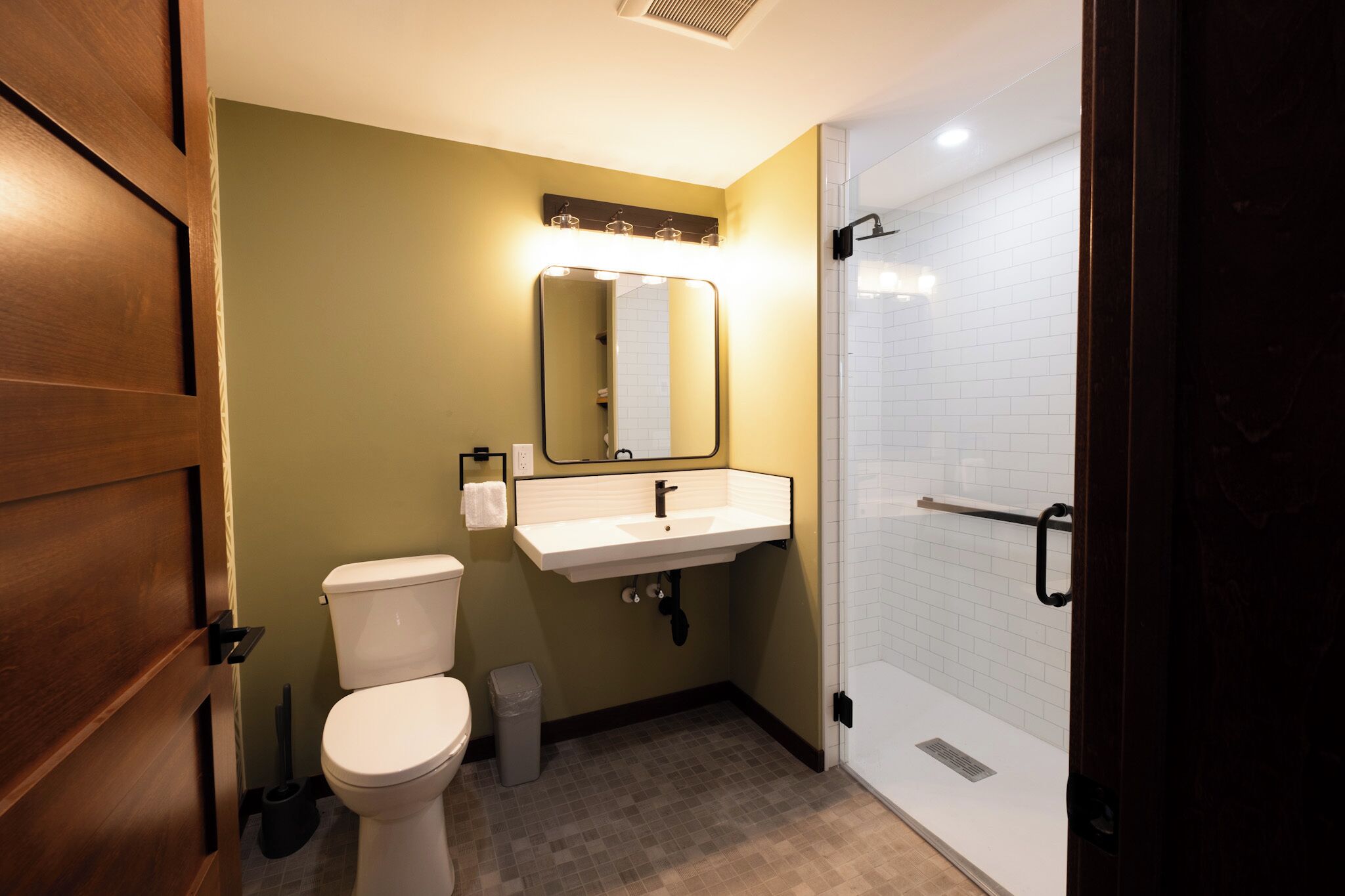 Un baño con inodoro, lavabo, espejo y ducha.