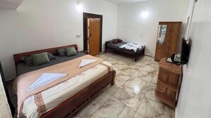 A bedroom with a large bed, a smaller bed, a wardrobe, and a ceiling fan.