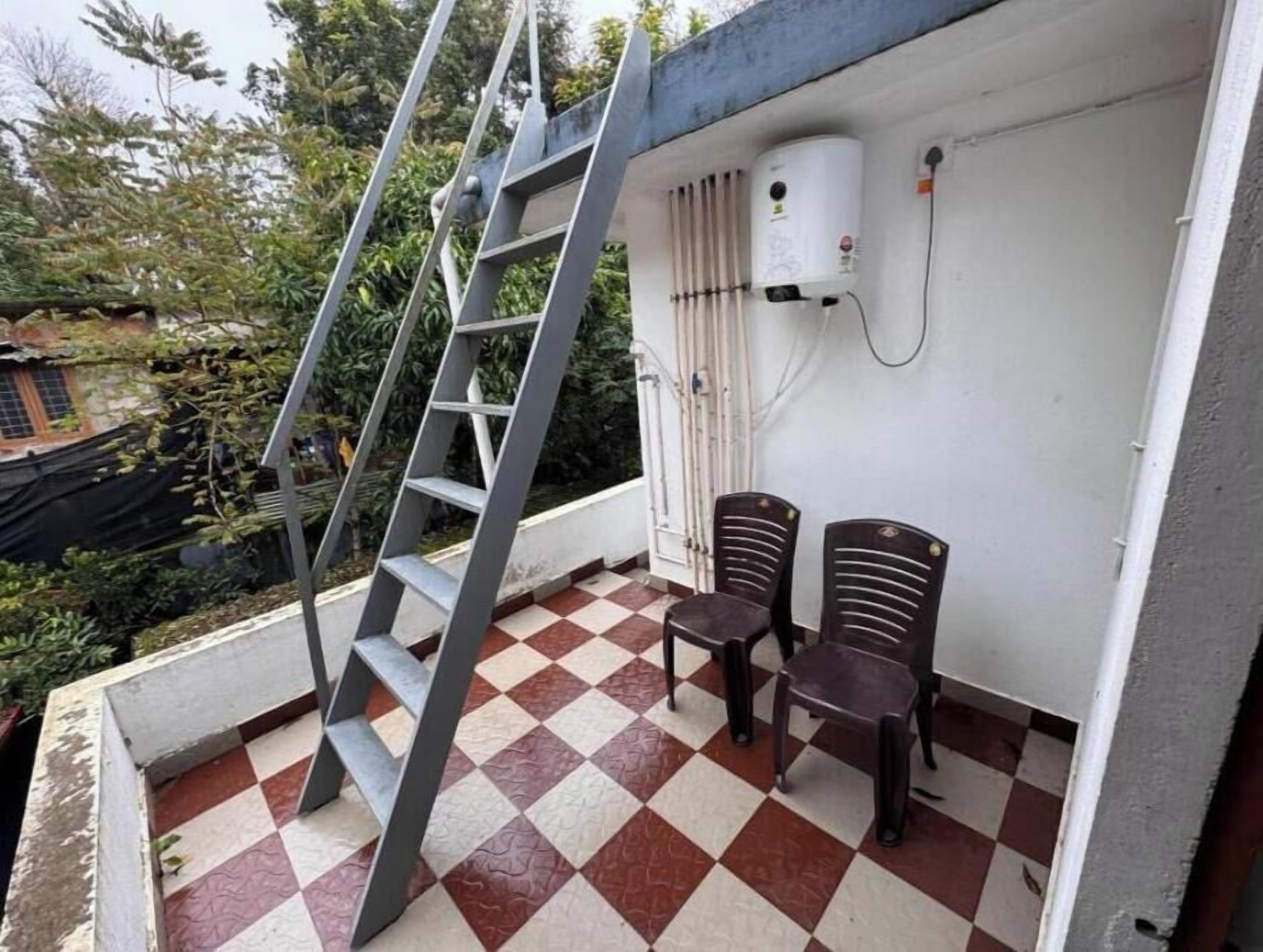 A balcony with a checkered floor, two chairs, a ladder, and an air conditioning unit.