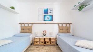 A bedroom with two single beds, a wooden chest of drawers, and wall art depicting ocean life.