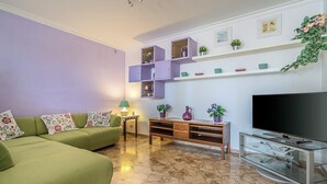 A living room with a green sofa, a TV stand, and a marble floor.