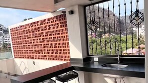 A modern kitchen with a bar area, a sink, and a view of a mountainous landscape. - New studio Apt. in the coveted Zona Romantica with roof top pool (Puerto Vallarta)