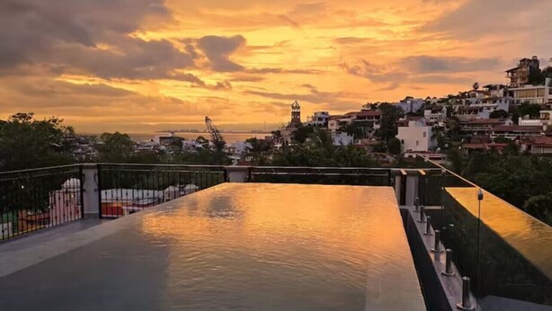 A rooftop pool with a view of a cityscape during sunset. - New studio Apt. in the coveted Zona Romantica with roof top pool (Puerto Vallarta)