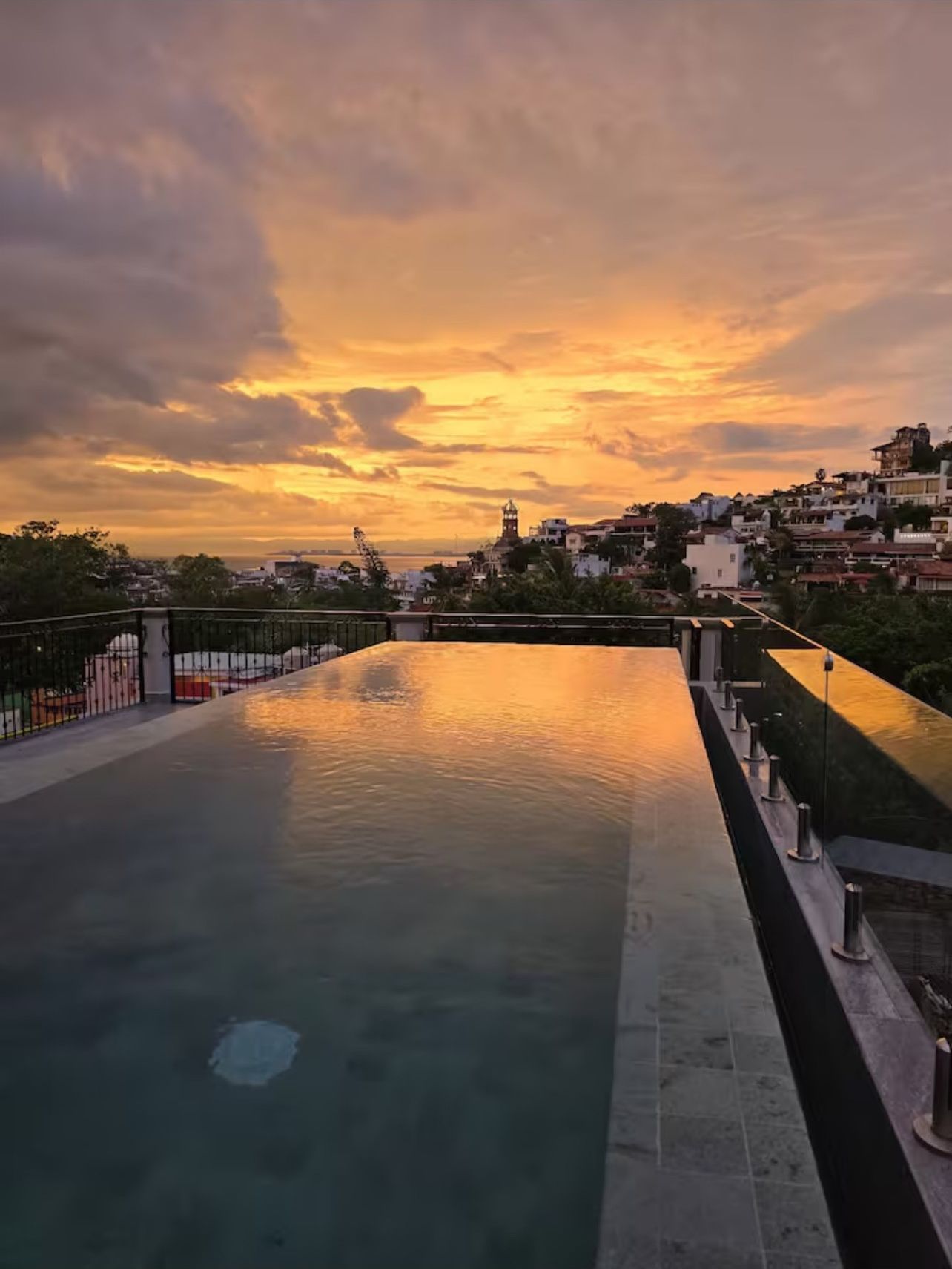 Piscina no terraço com vista para a paisagem urbana ao pôr do sol.