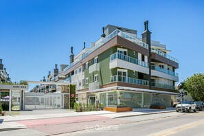 A multi-story residential building with balconies, a ground-level entrance, and a visible address sign. - Seaside Condominium in Campeche-florianopolis SHR (Florianópolis)