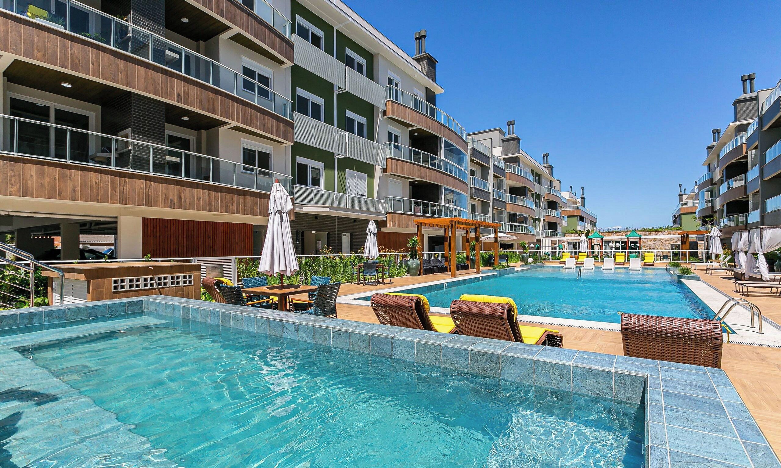 Un hotel con piscina, zona de estar exterior y varios balcones.