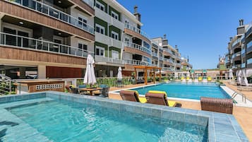 A hotel with a swimming pool, outdoor seating, and multiple balconies.