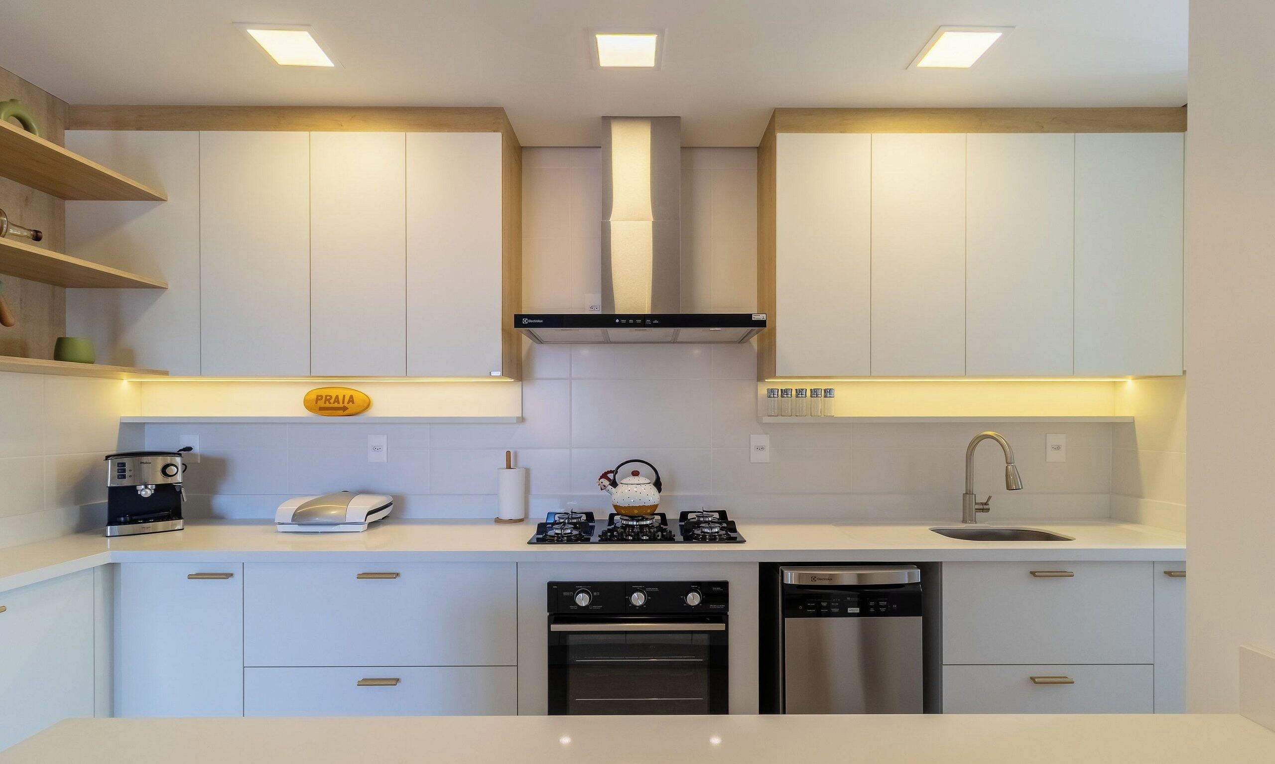 Cocina moderna con armarios blancos, horno empotrado, lavavajillas y cafetera.