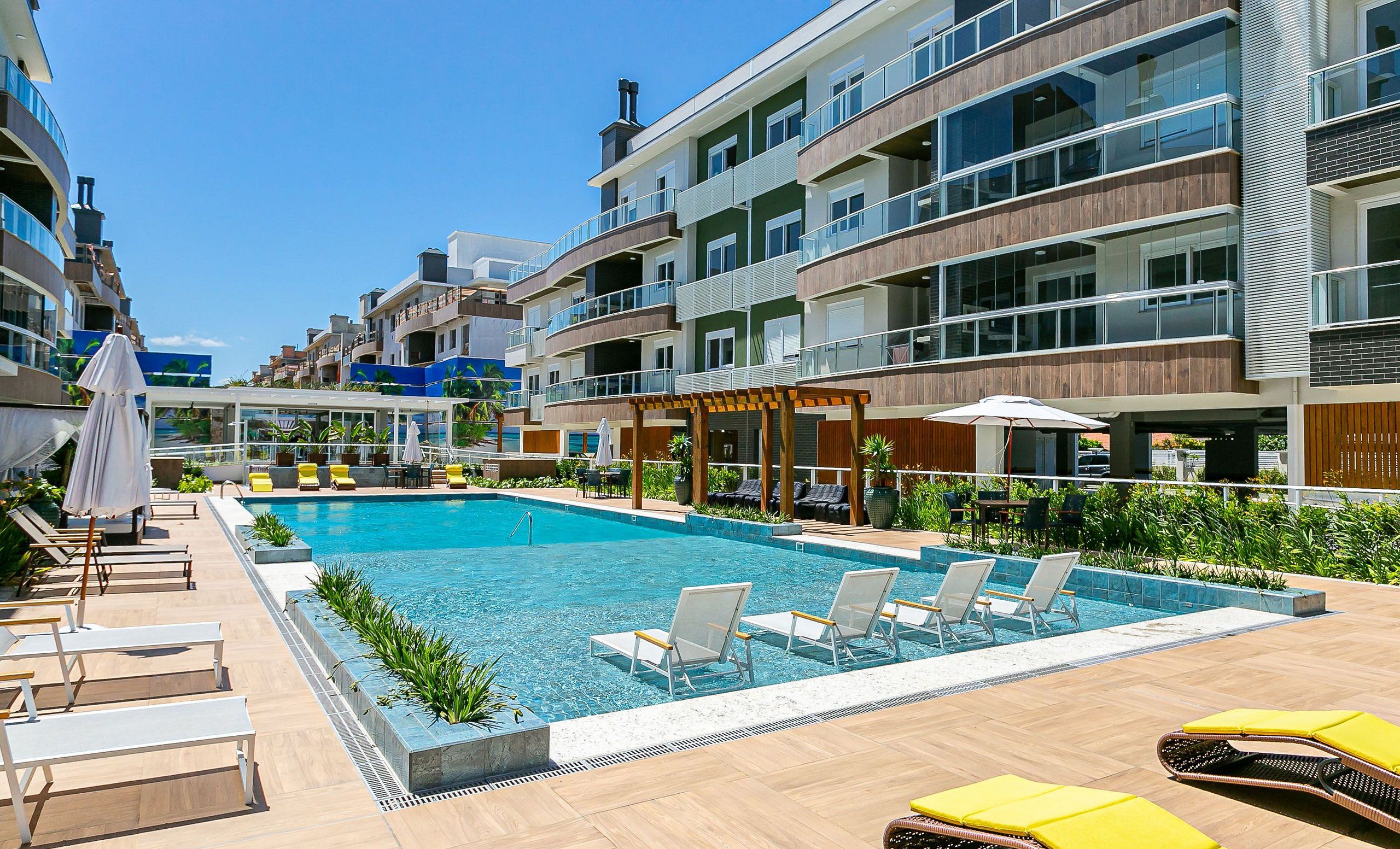 Un hotel moderno con piscina, mobiliario exterior y restaurante.