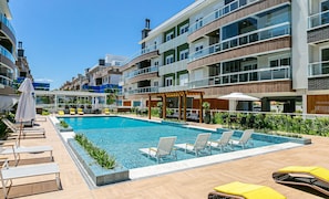 A modern hotel with a swimming pool, outdoor seating, and a restaurant. - Seaside Condominium in Campeche-florianopolis SHR (Florianópolis)