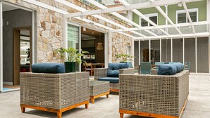 Un espace extérieur aménagé, abrité et doté de mobilier en osier et de plantes en pot.