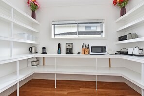Cocina compacta con armarios blancos, una ventana sobre la encimera y diversos electrodomésticos, como una cafetera, microondas y tostadora.
