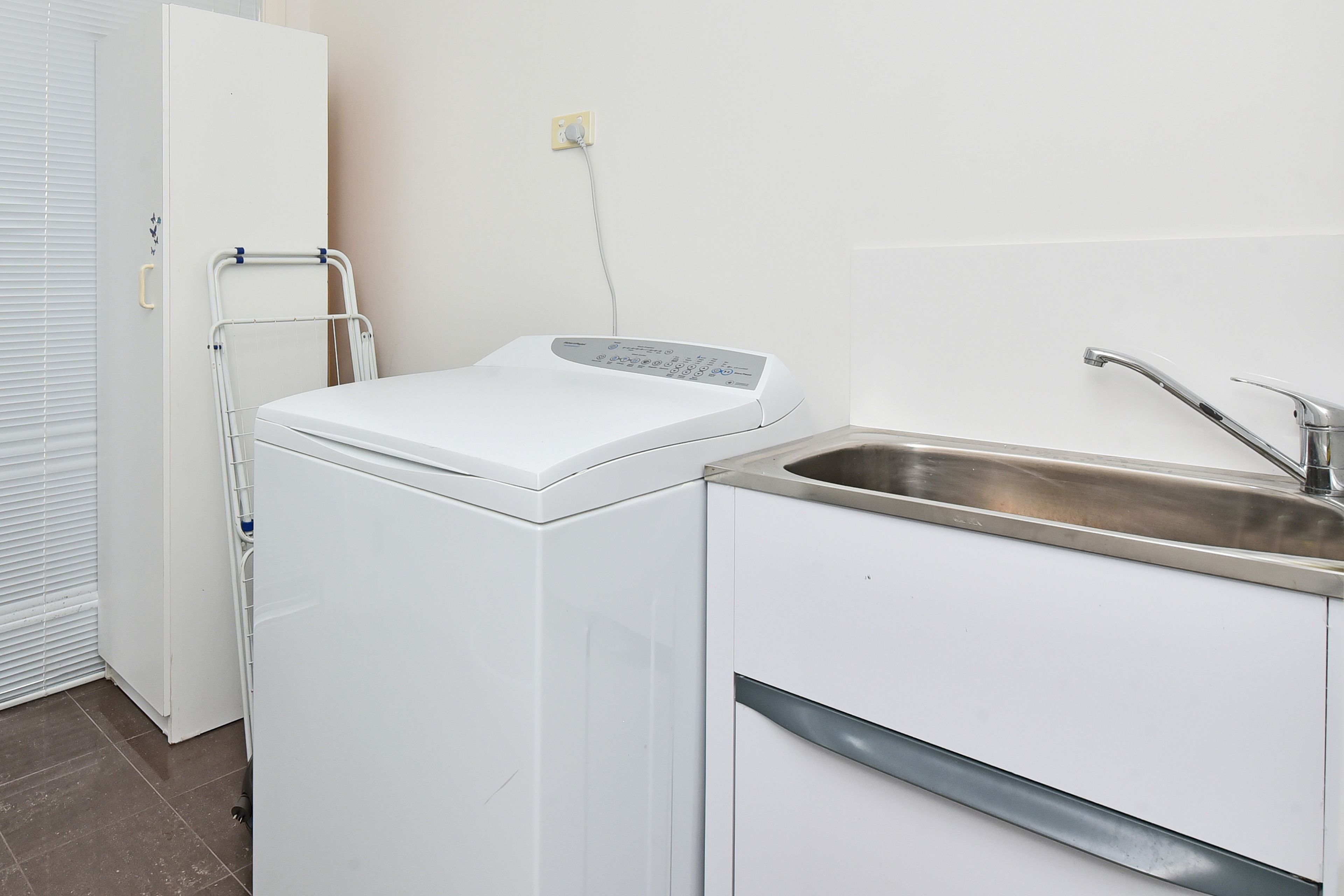 A compact kitchen with a built-in washing machine, a sink, and a power outlet on the wall.
