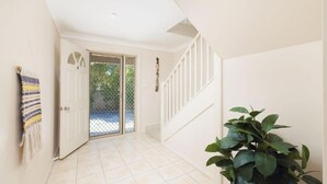 Ein Flur mit einer weißen Tür, einer Treppe und einem Blumentopf.