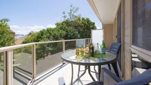 A balcony with a glass table, chairs, and bottles. - Tomaree Escape Family GetawayIn Nelson Bay (Nelson Bay)