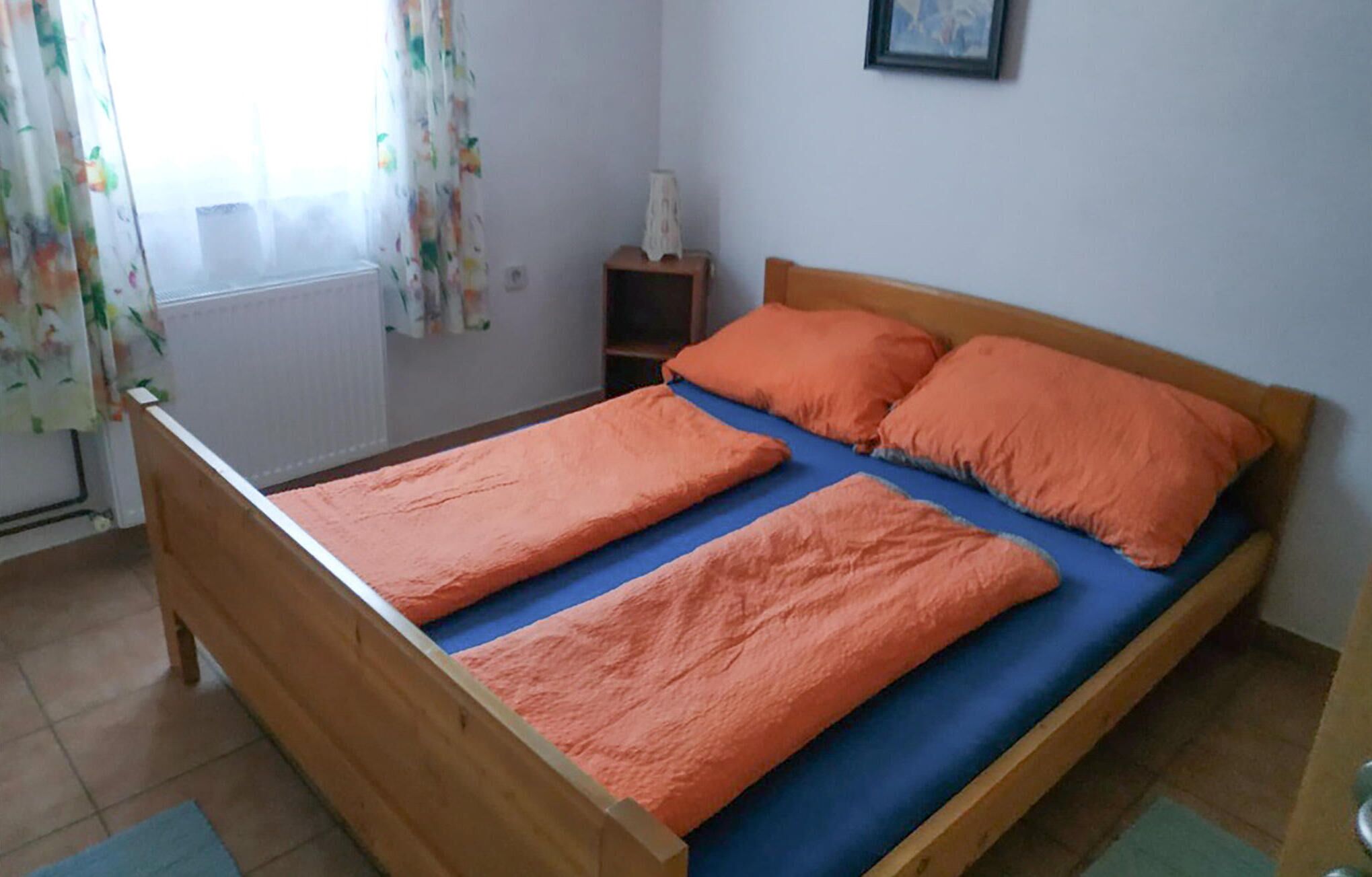 A single bed with two orange pillows and a blue mattress cover.