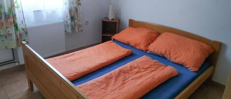 A single bed with two orange pillows and a blue mattress cover.