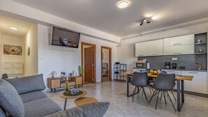 A modern living room with a grey sofa, a coffee table, and a TV mounted on the wall.