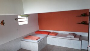 A small, compact room with a bed, a bench, and a shelf with decorative items. - Excellent house on Águas Lindas beach (Itacuruça Island) (Itacuruçá Mangaratiba)