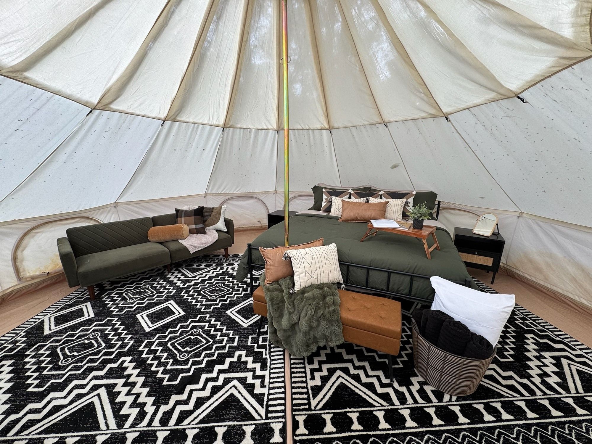A tent interior with a sofa, a small table, and a patterned rug.