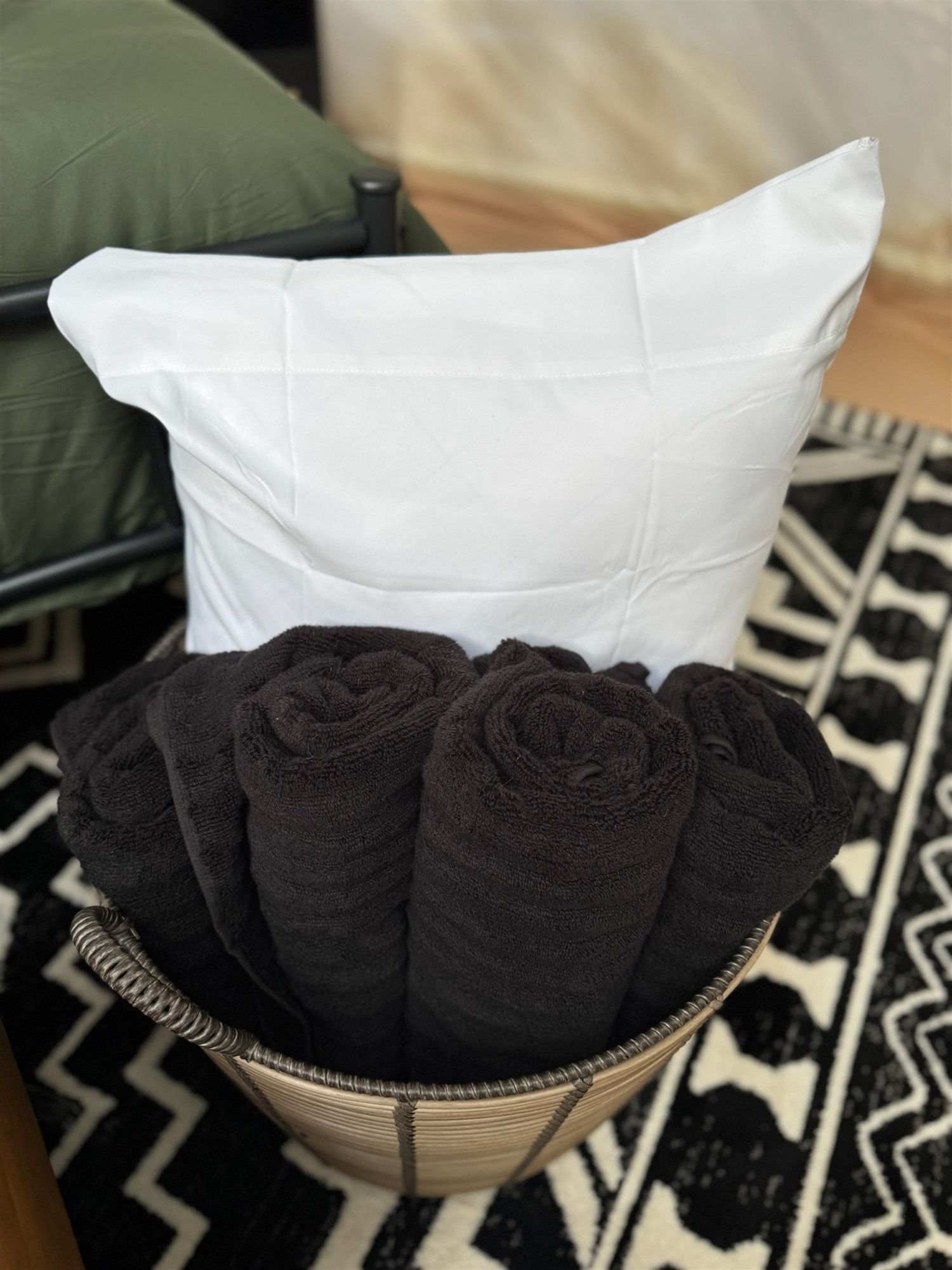 Un almohadón blanco sobre una silla con un tapete de diseño blanco y negro.