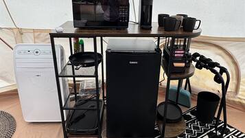 A compact kitchenette with a microwave, coffee maker, and small refrigerator.