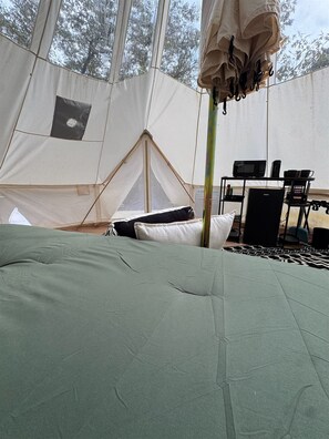 Ein Zelt mit einem Bett, einem Tisch mit elektronischen Geräten und einem Stuhl.