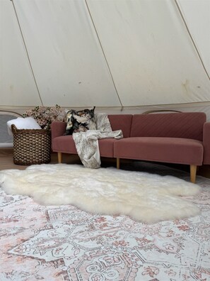 A room with a sofa, a woven basket, and a fur rug.
