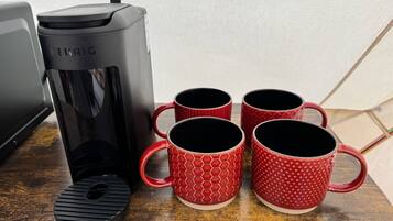 Een Keurig koffiezetapparaat met vier rode mokken op een houten oppervlak.