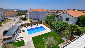 Un quartier résidentiel doté d’une piscine, de chaises longues et offrant une vue sur la mer.