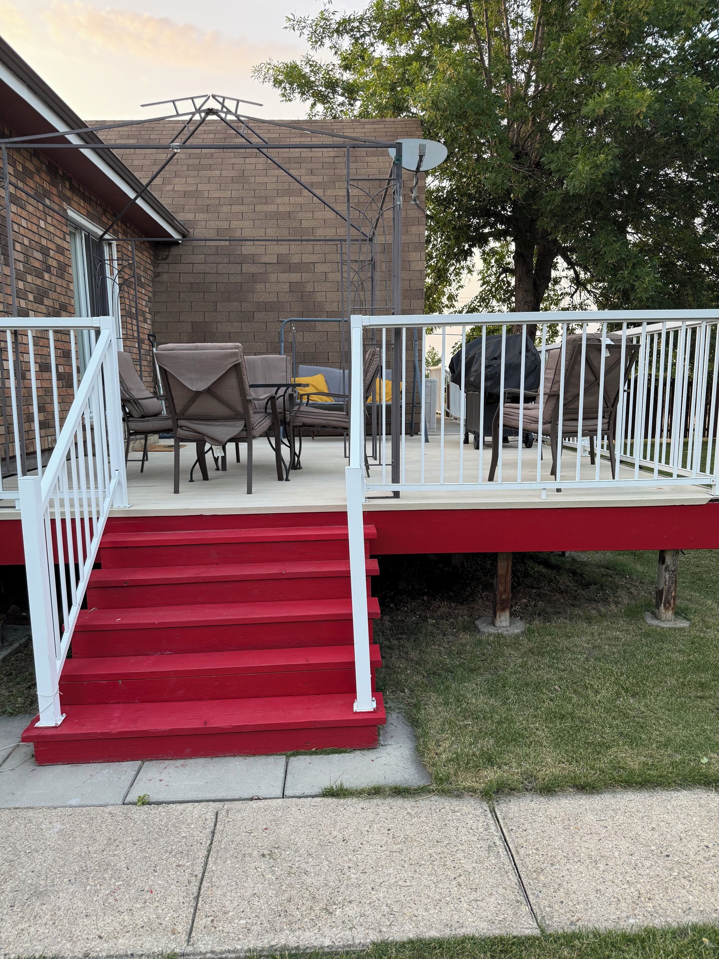 Une terrasse couverte avec des marches rouges, du mobilier d’extérieur et une antenne parabolique.
