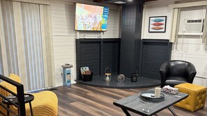A modern living room with a fireplace, wooden floors, and a TV mounted on the wall.