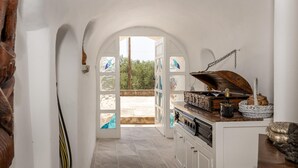 Un pasillo estrecho con paredes blancas y una puerta de madera que da a un espacio exterior.