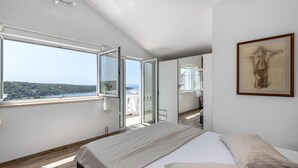 A bedroom with a large bed, a view of the sea, and a painting on the wall. - Pet friendly apartment in Kampor with WiFi (Kampor)