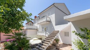 A two-story building with a white exterior, a balcony on the upper floor, and a set of stone steps leading to the entrance. - Pet friendly apartment in Kampor with WiFi (Kampor)