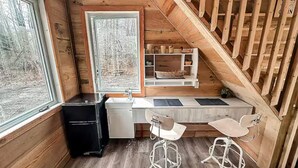 A compact kitchen with a sink, two bar stools, and a window.
