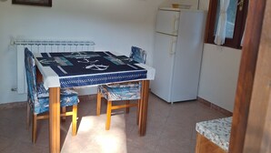 Un coin repas avec une table et des chaises, un réfrigérateur et deux tableaux encadrés au mur.