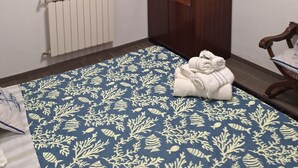Une petite pièce comprenant un lit, une armoire, un radiateur et une fenêtre avec des rideaux.
