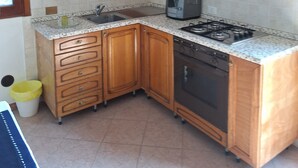 Une cuisine avec des meubles de rangement en bois, une cuisinière à gaz, une machine à café et un évier.