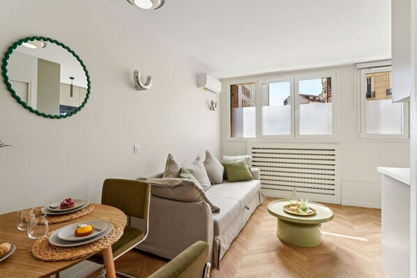 Un espace de vie compact comprenant un coin repas, un canapé et une petite table agrémentée d’un objet décoratif.