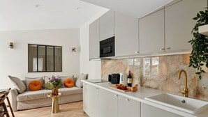 Een moderne keuken met witte kastjes, een marmeren spatwand en een ingebouwde magnetron.