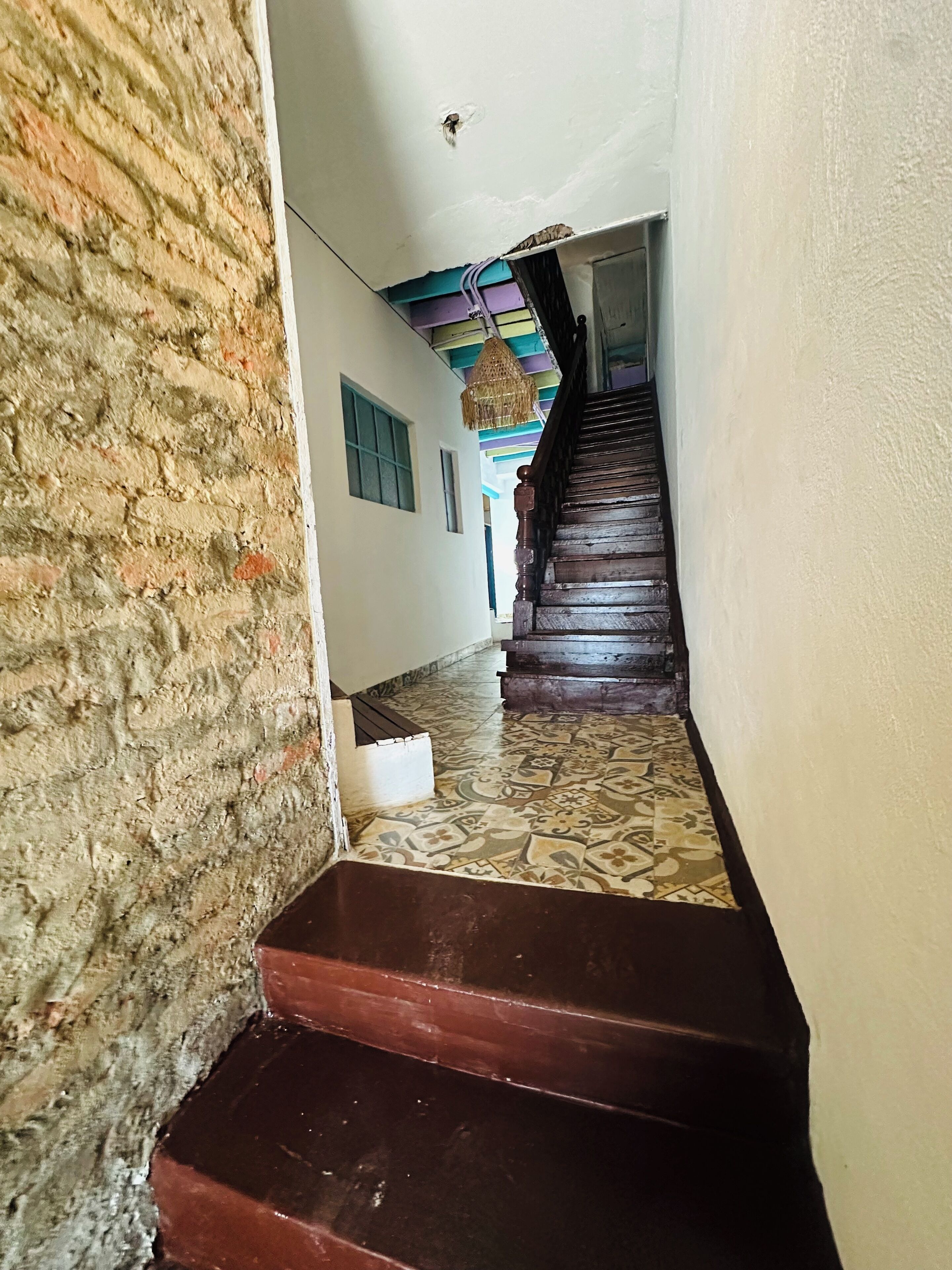 A staircase with a patterned floor leading to a room with a colorful ceiling.