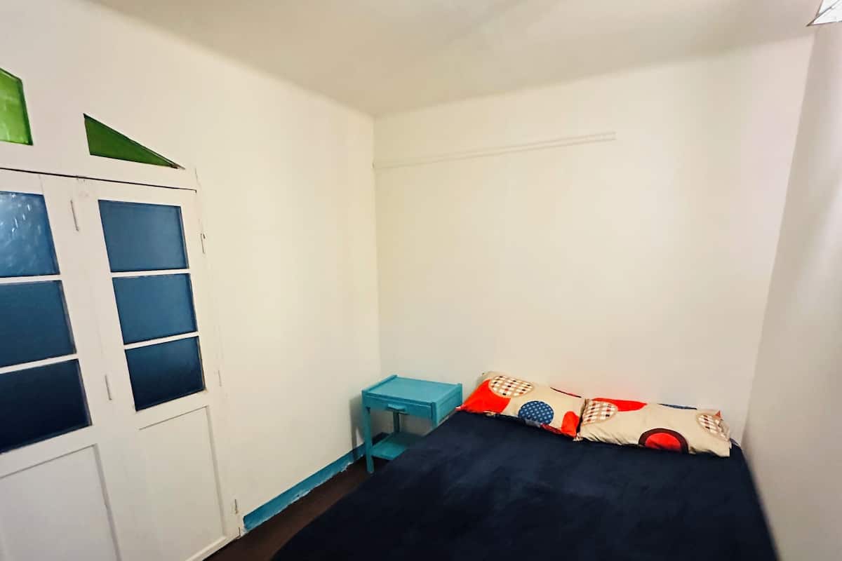 Ein Schlafzimmer mit einem Bett, einem kleinen Tisch und einem Kleiderschrank mit Glastüren.