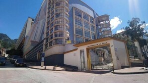 A modern building with a curved facade and multiple windows, featuring a prominent entrance with a gate. - AQUI ME QUEDO here I stay (Bogota)