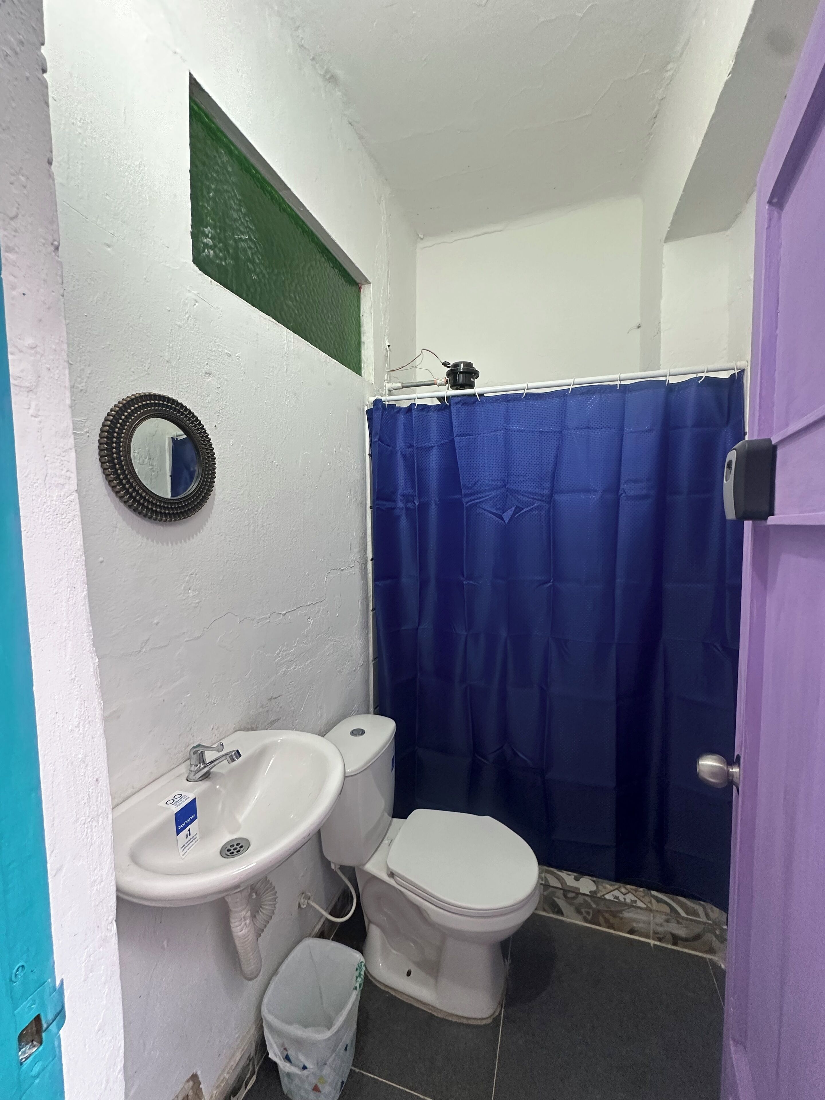 A small bathroom with a white sink, toilet, and a blue shower curtain.