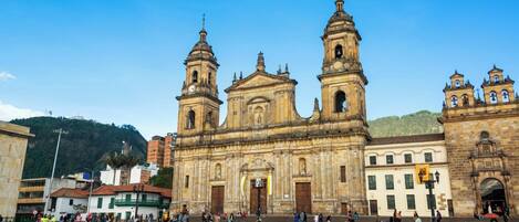A historic church with two towers and a large open plaza with pigeons.